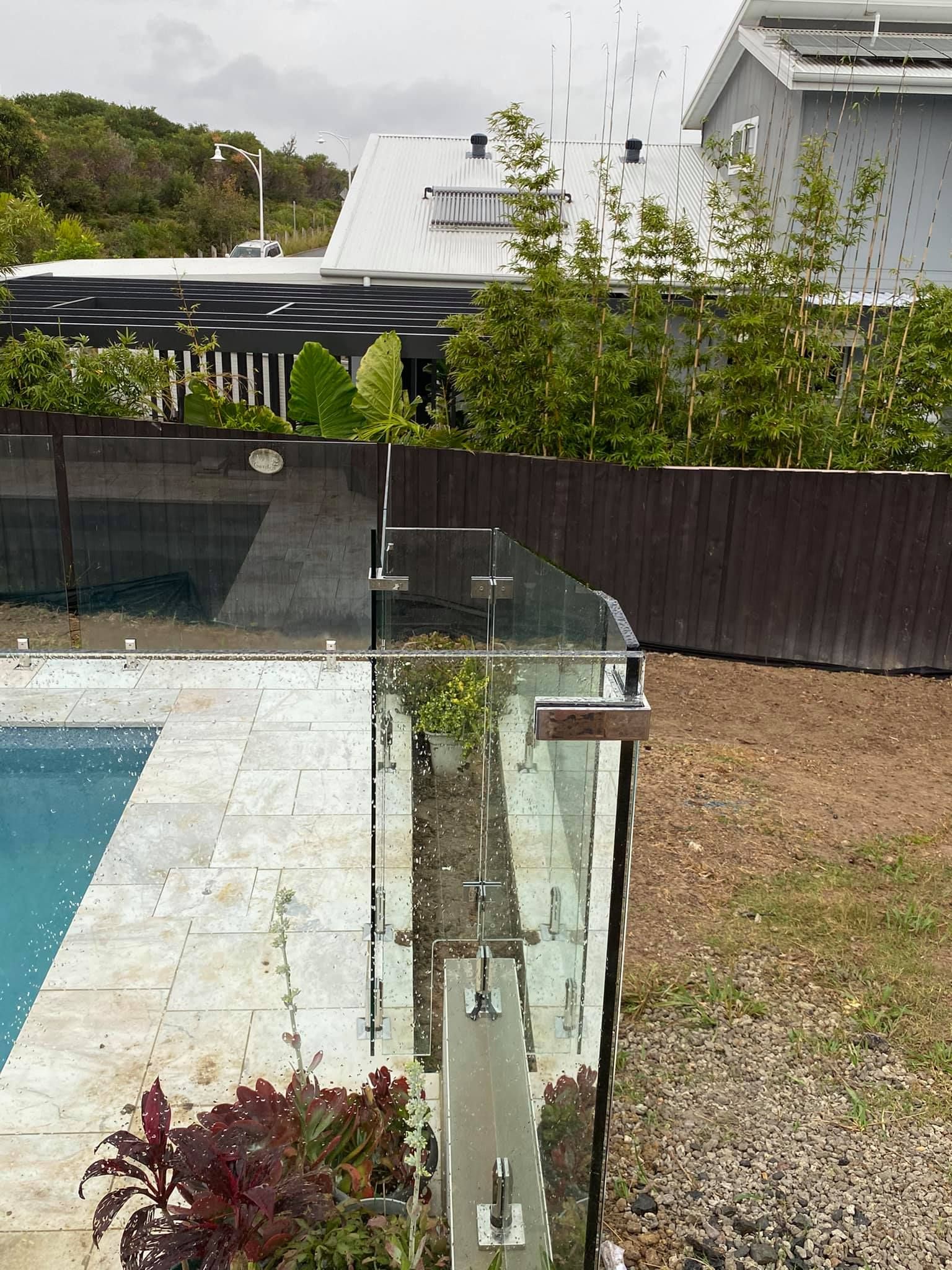 Glass Pool Fence Next to A Pool with A View of A House and Yard — Master Glass & Glazing in Charlestown, NSW