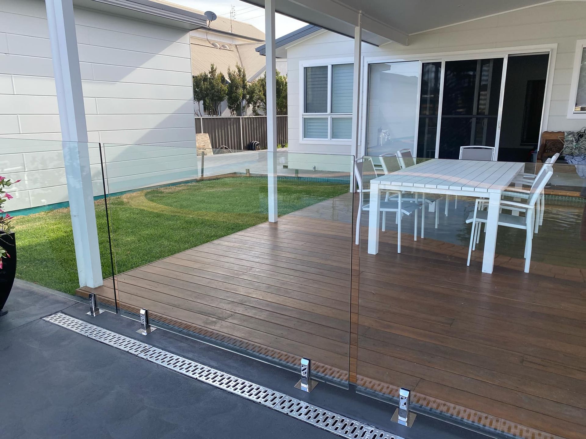 Covered Deck with Dining Table, Glass Railing, and Grass Yard, Next to A Home — Master Glass & Glazing in Maitland, NSW
