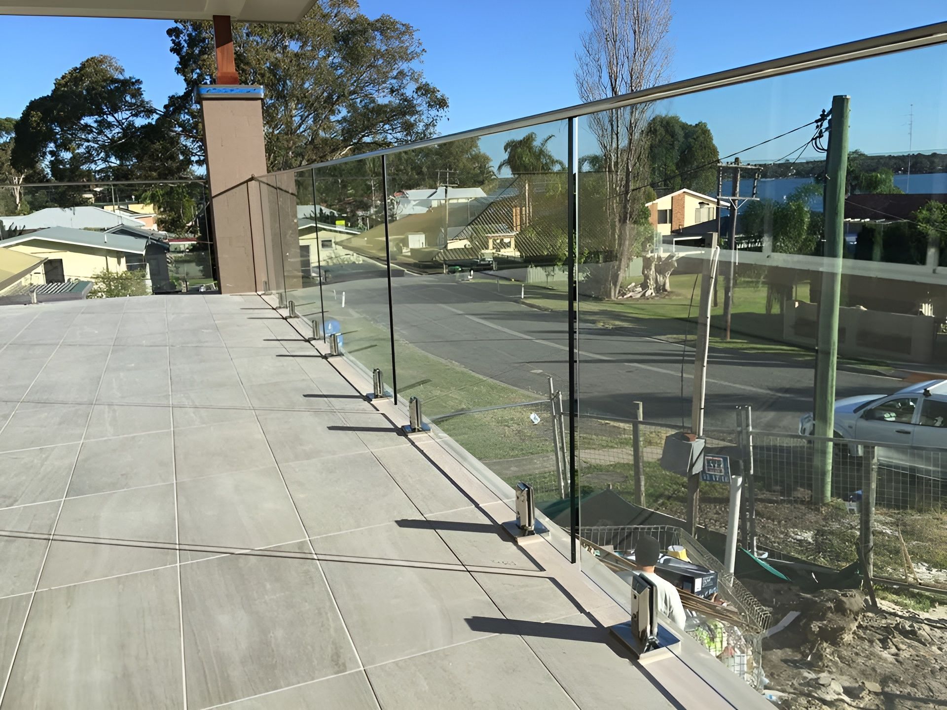 A Glass Railing on A Tiled Patio Overlooking a Residential Street — Master Glass & Glazing in Newcastle, NSW