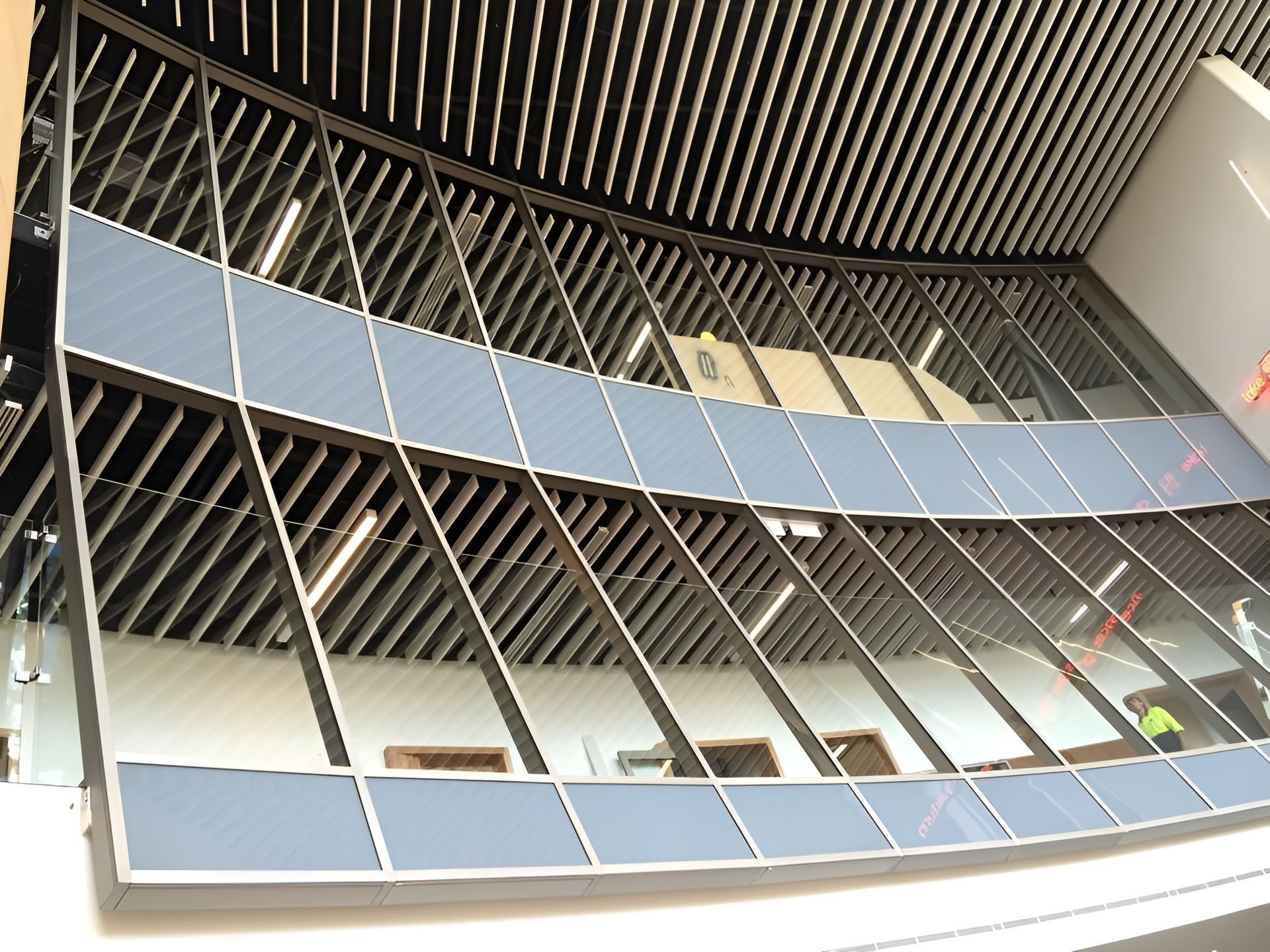 Curved Glass Facade with Diagonal Metal Supports and Blue Panels — Master Glass & Glazing in Mayfield, NSW
