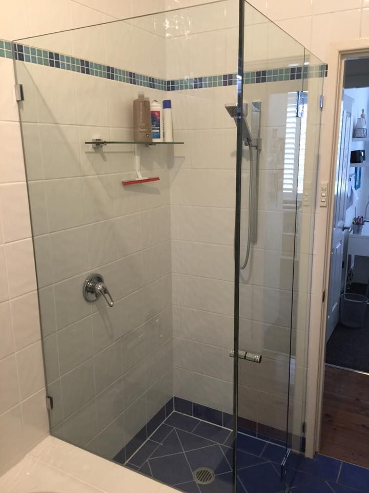 Glass Shower Enclosure with Blue Tile Floor and Accent, Toiletries on Shelf — Master Glass & Glazing in Merewether, NSW
