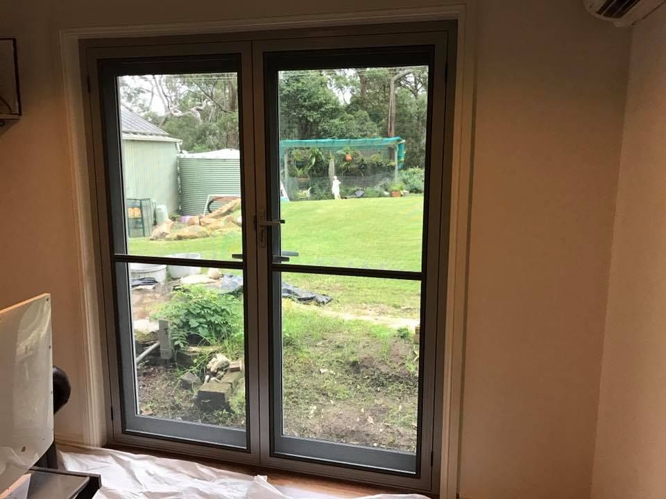 Double Glass Doors with Screen Doors Open to A Backyard with Green Grass — Master Glass & Glazing in Toronto, NSW