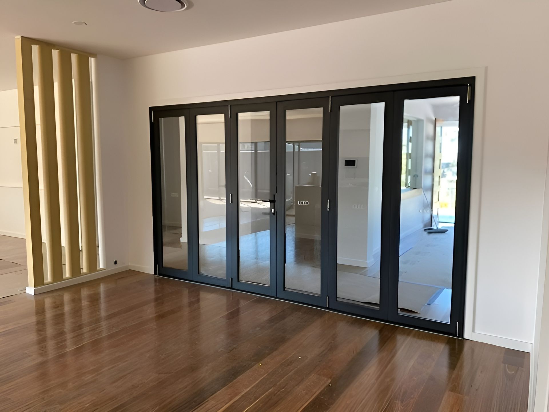 Folding Glass Doors with Black Frames in A Room with Hardwood Floors — Master Glass & Glazing in Newcastle, NSW