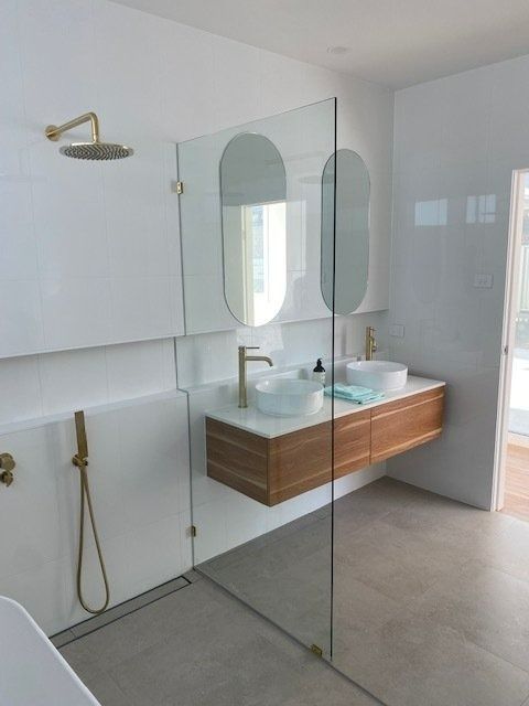 Modern Bathroom with Floating Wooden Vanity, Oval Mirrors, Glass Shower — Master Glass & Glazing in Newcastle, NSW