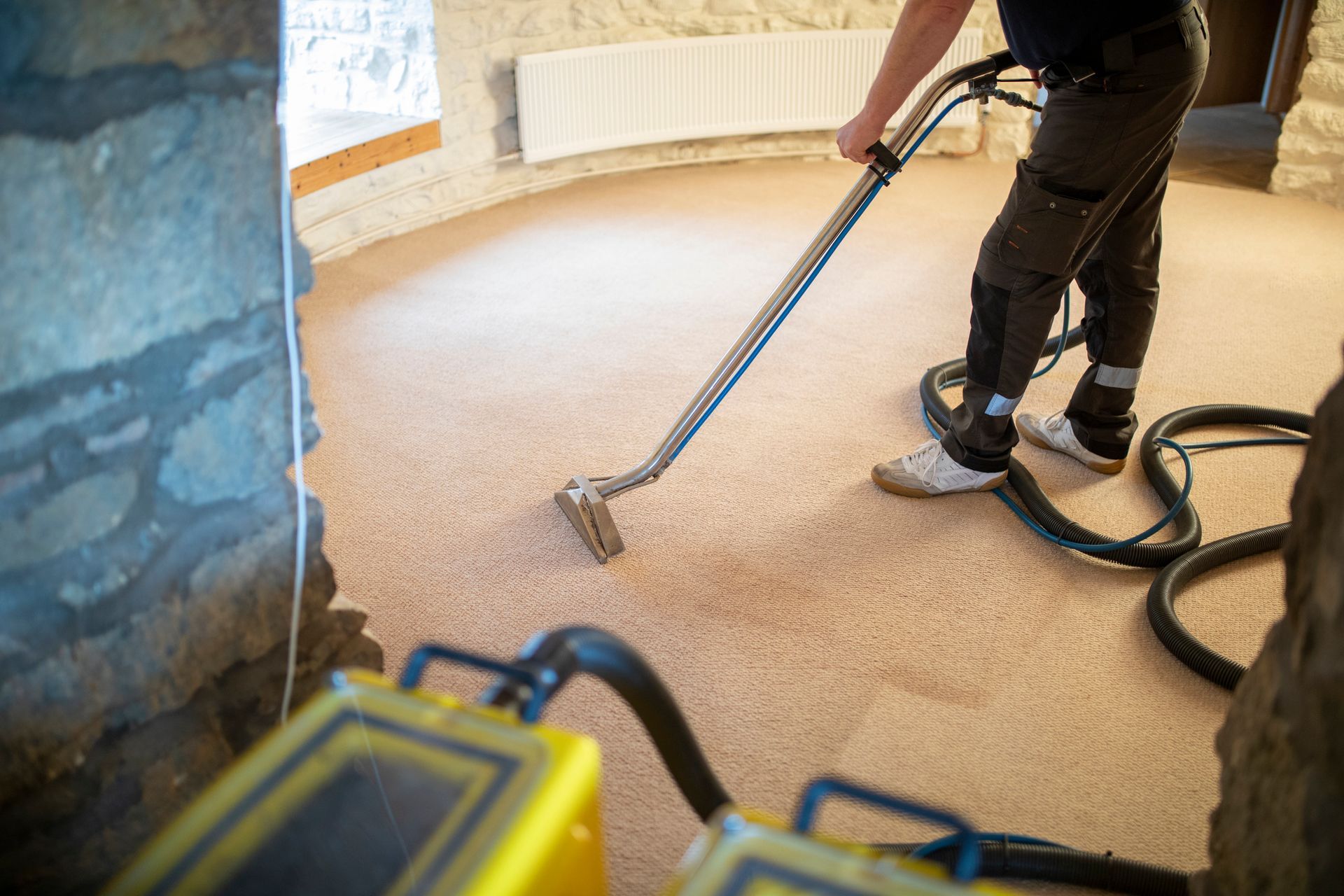 A man is cleaning a carpet with a vacuum cleaner.