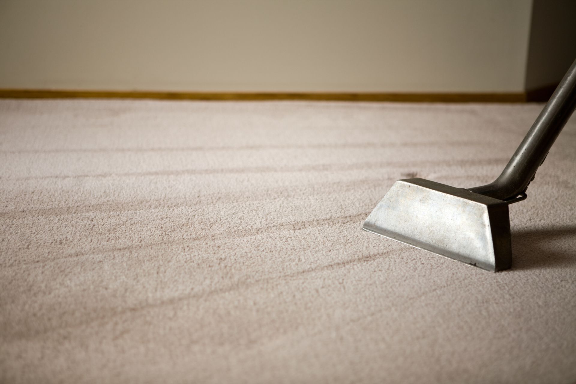 A vacuum cleaner is being used to clean a carpet.