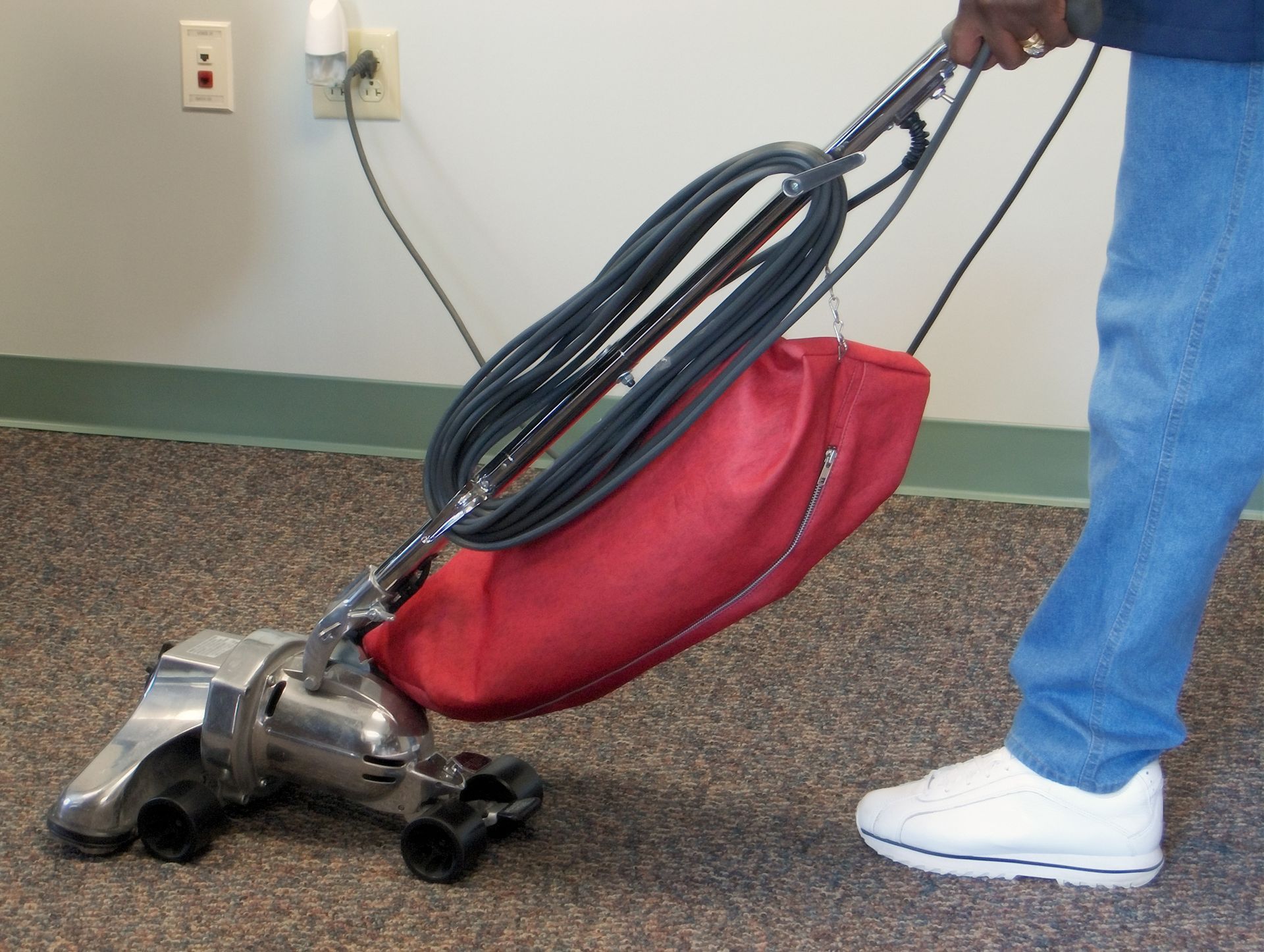 A person is using a vacuum cleaner on a carpeted floor