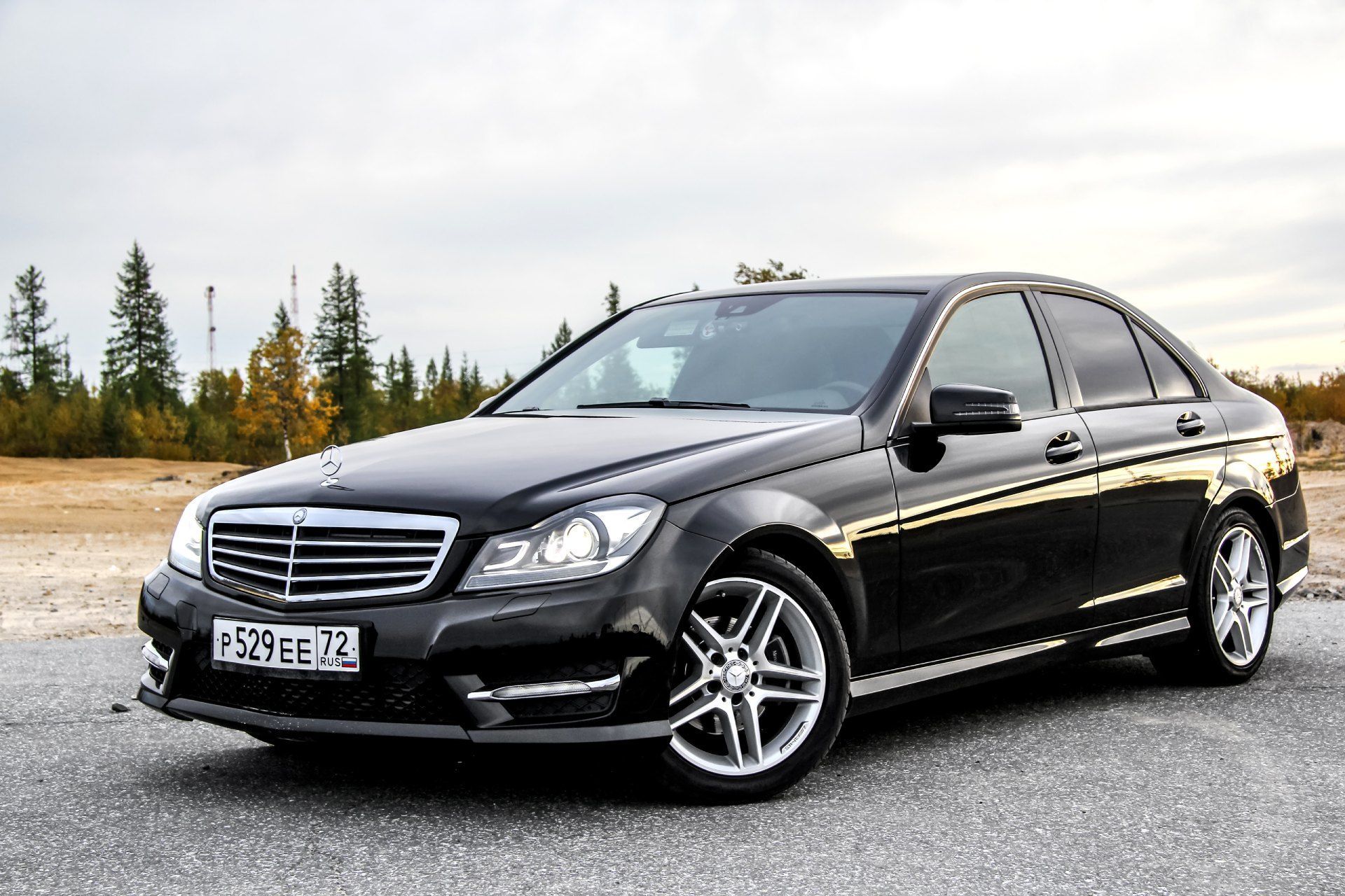 A black mercedes benz c class is parked on the side of the road.