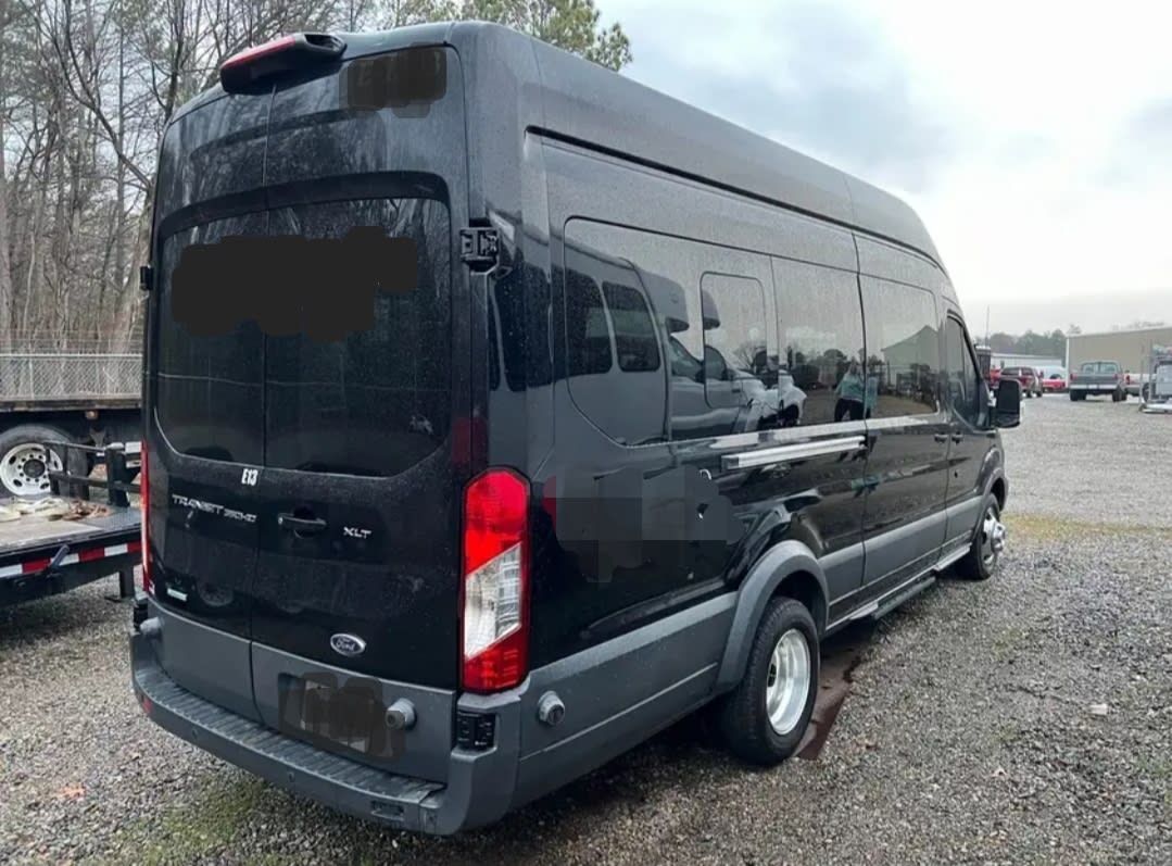 A black van is parked in a gravel lot.
