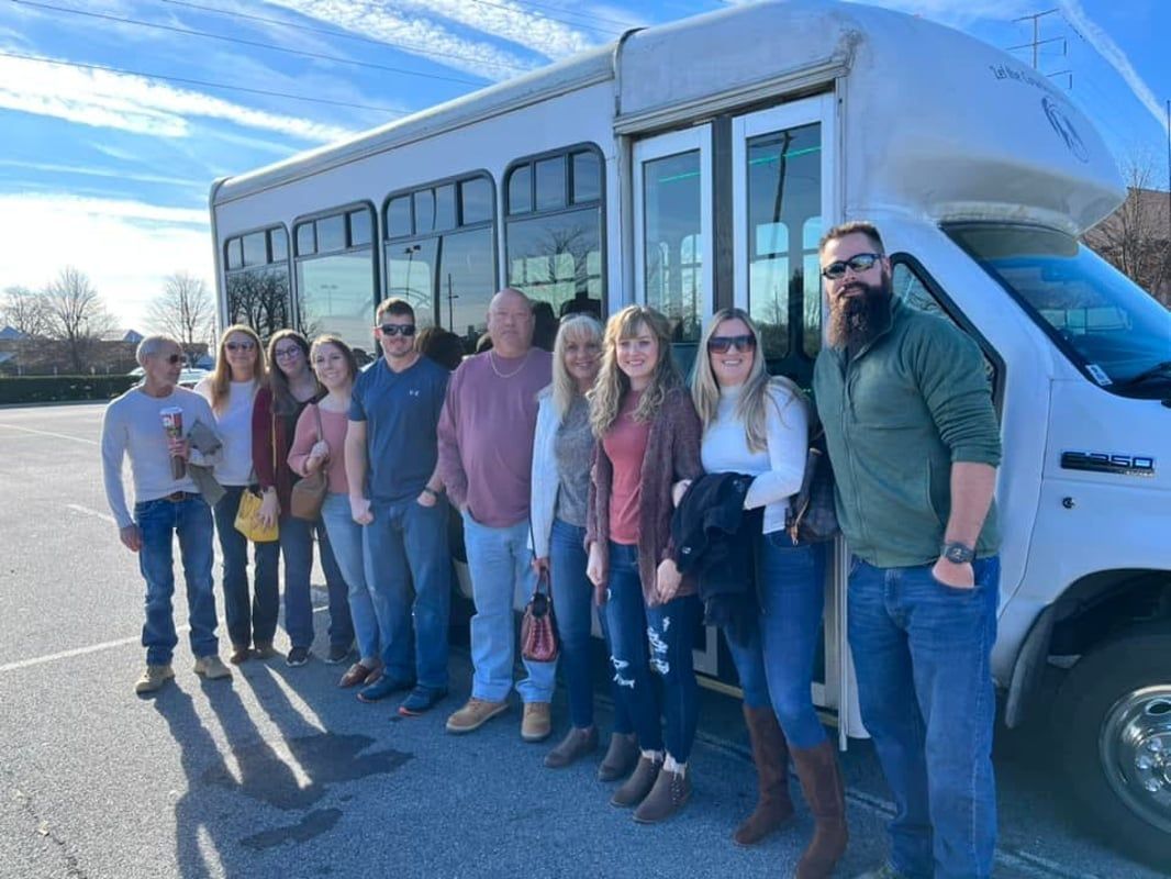 A group of people are standing in front of a white bus.