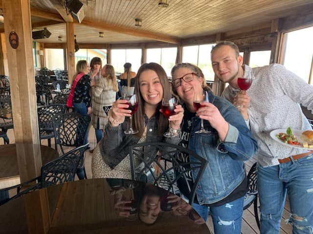 A group of people are sitting at a table holding wine glasses.