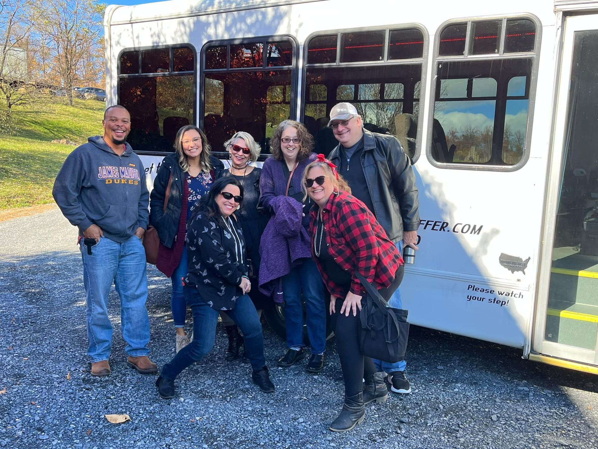 A group of people are posing for a picture in front of a bus.