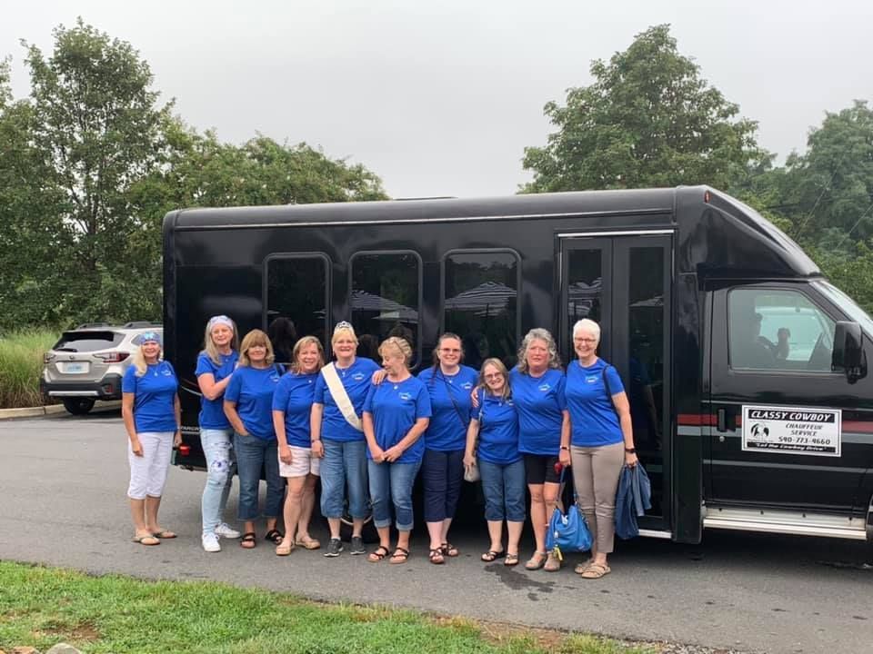 A group of women are standing in front of a black van.