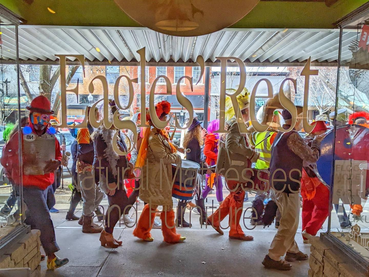 A parade of people walking past the window at Eagles' Rest Natural Mattresses and Furniture inLawrence, Kansas.