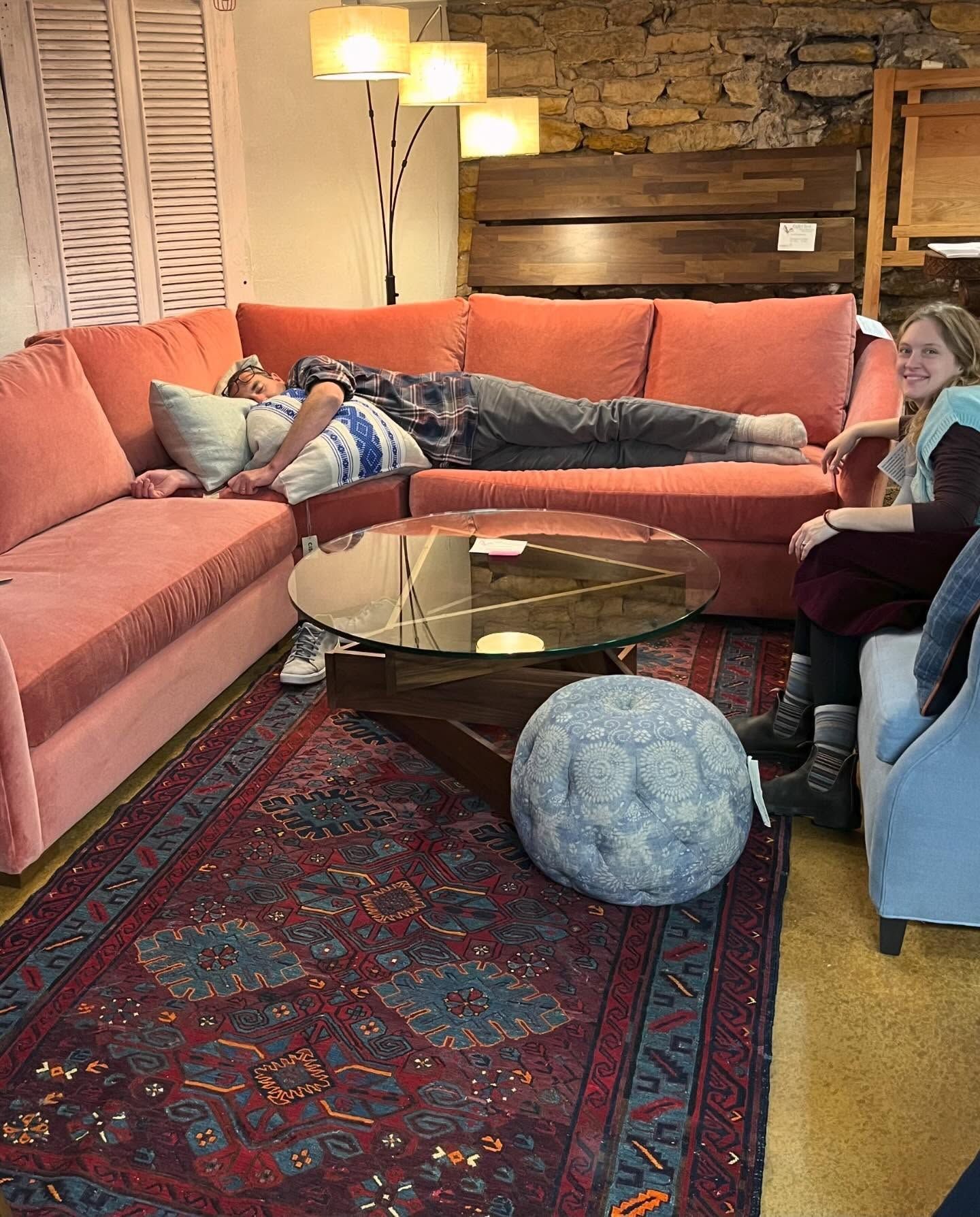 Person sleeping on a large pink sectional sofa at Eagles' Rest Natural Mattresses and Furniture inLawrence, Kansas.