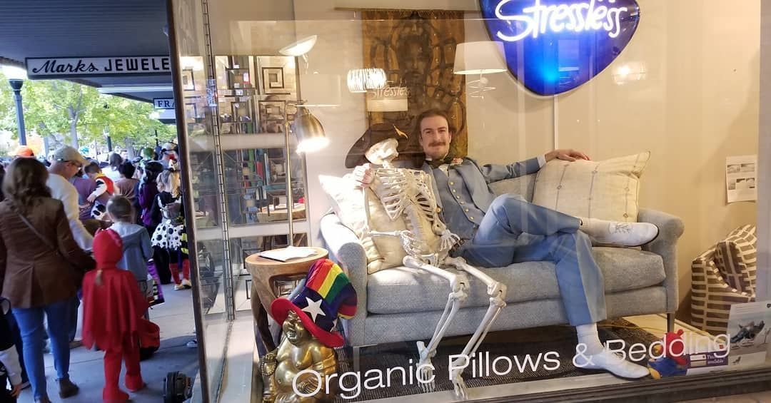 Man sitting on a couch with a skeleton at Eagles' Rest Natural Mattresses and Furniture inLawrence, Kansas.