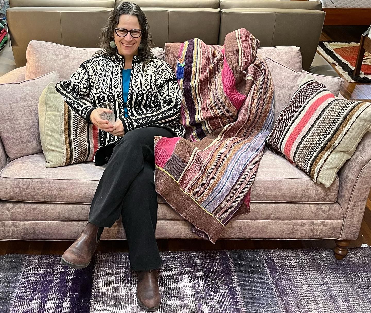 Diane Gercke sitting on a beautiful couch for sale at Eagles' Rest Natural Mattresses and Furniture.