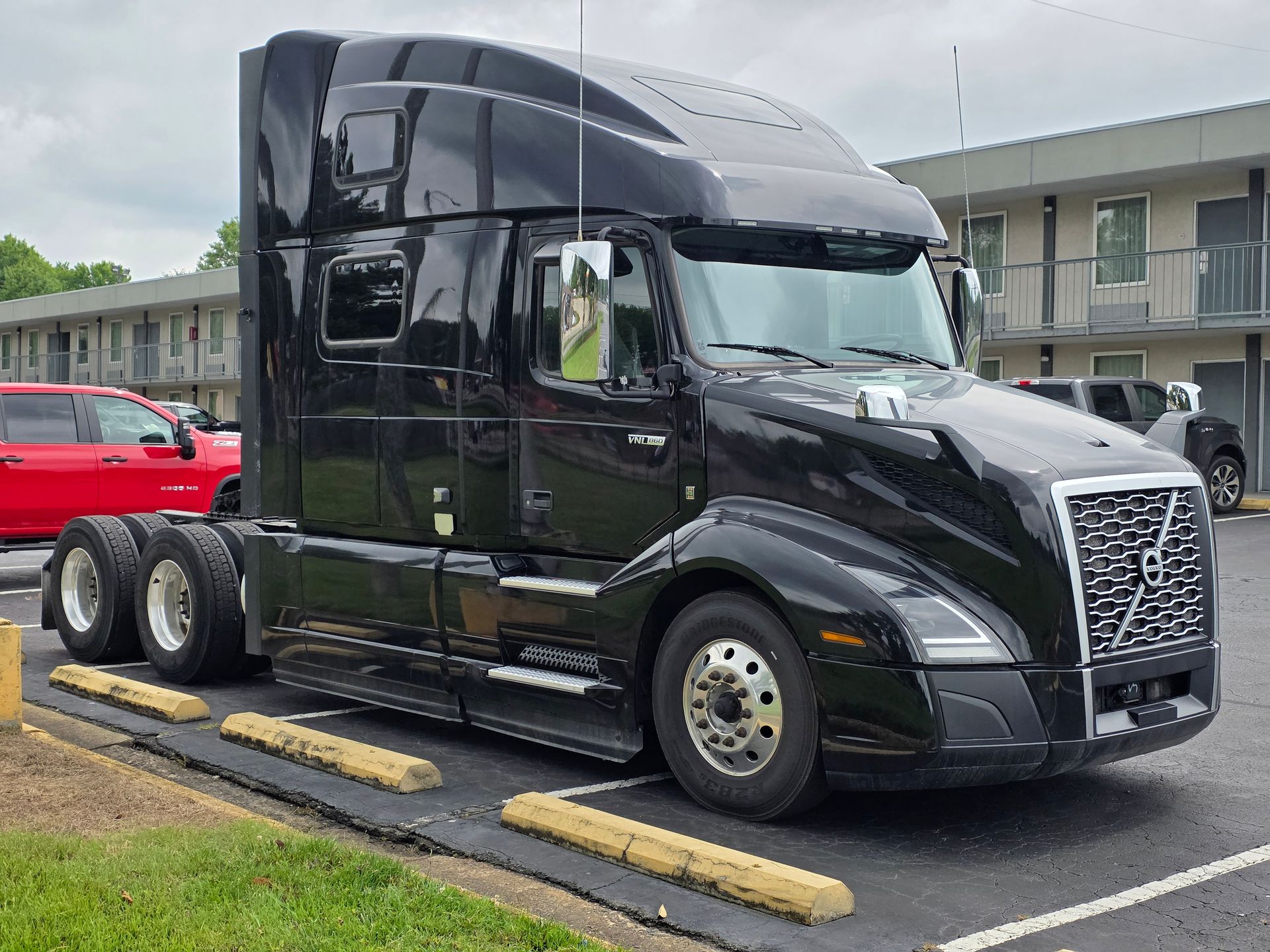 Black Volvo semi-truck parked in front of a motel.