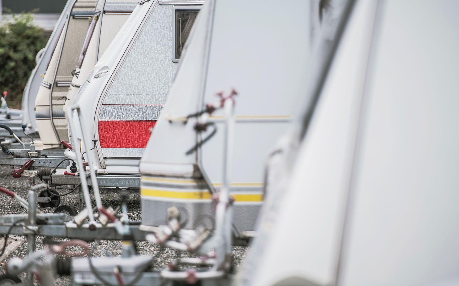 Row of white RVs parked outside, some with red and yellow accents.