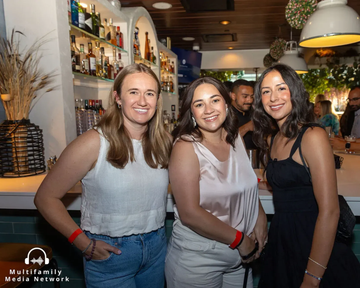 Person wearing glasses and headphones sits at a desk with a microphone, looking to the side.