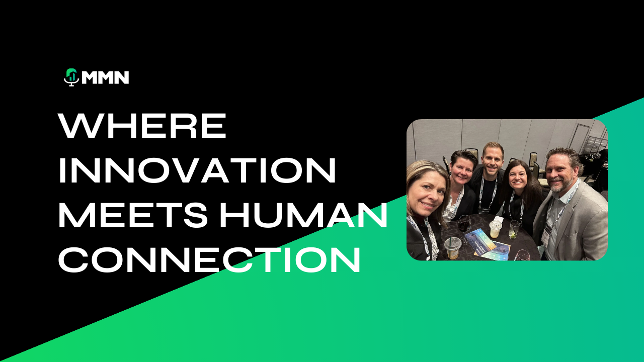 Five people smiling, gathered around a small table, some holding drinks, at a conference.