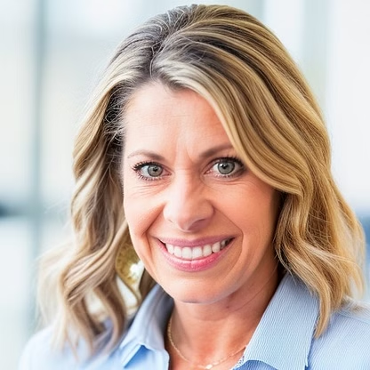 Woman with blonde wavy hair, smiling, wearing a blue shirt and gold jewelry.