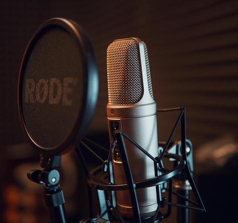 Silver studio microphone with pop filter in a recording studio setting.
