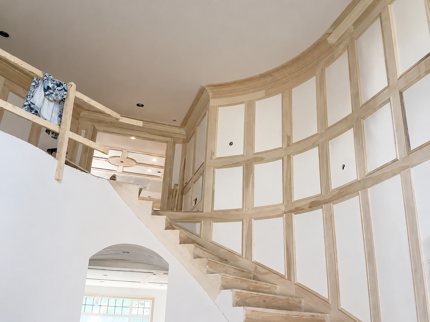 Curved staircase in a bright, unfinished interior with white walls and wood framing