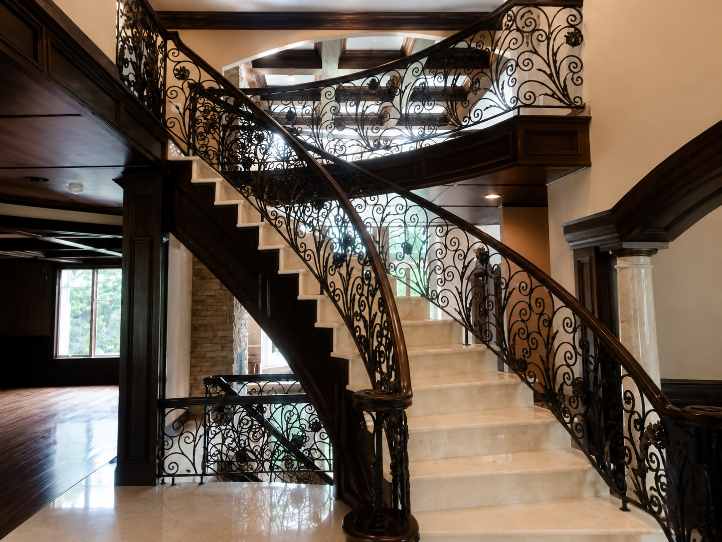 Elegant staircase with ornate wrought-iron railings in a spacious home interior