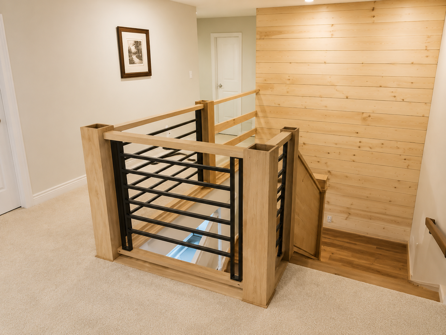 Indoor stair landing with wooden railings and black cable balusters beside a stairwell opening
