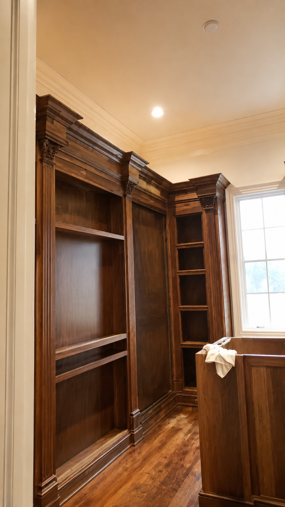 Wood-paneled library with built-in shelves, a cabinet, and a window letting in daylight