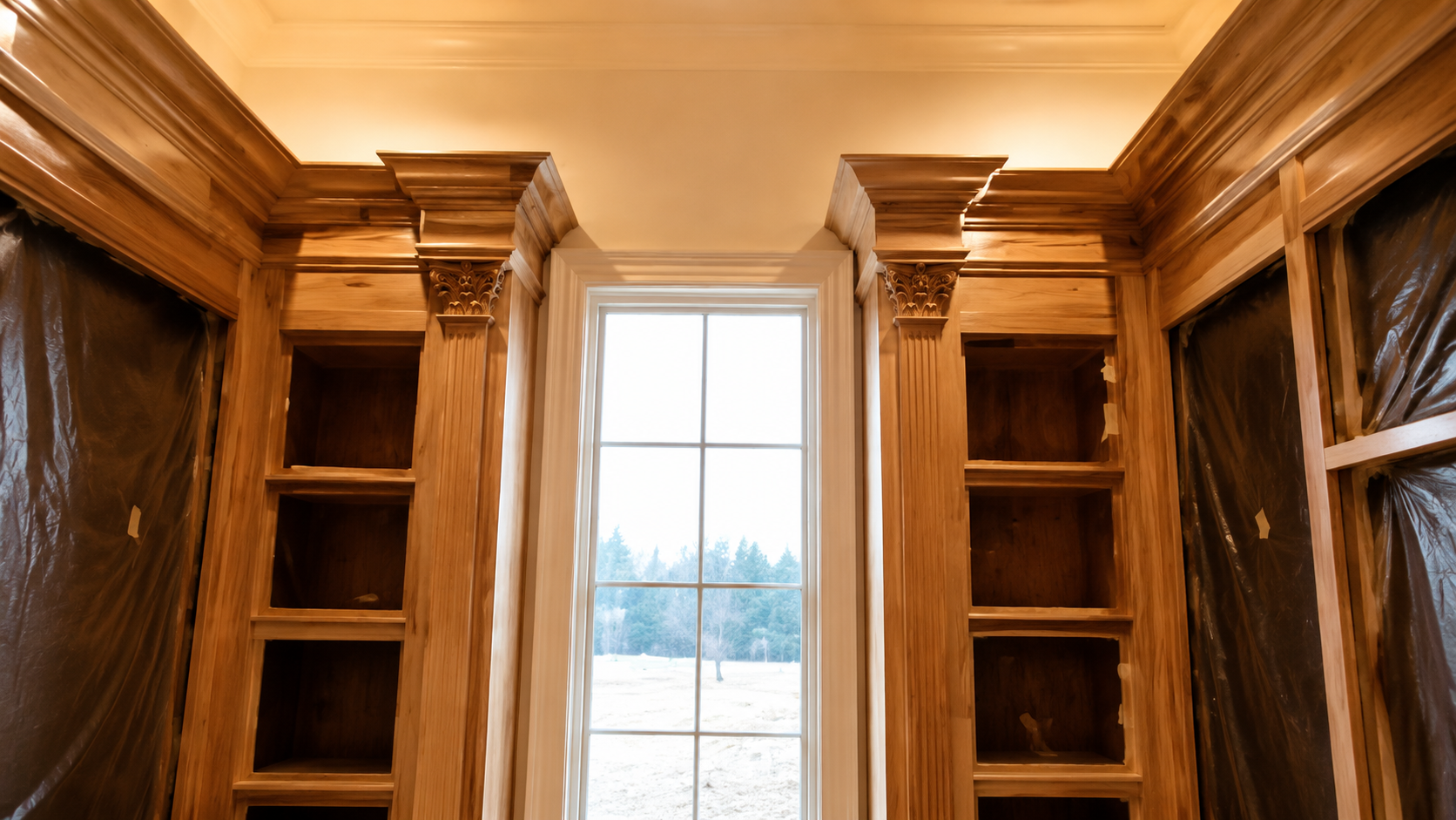 Wood-paneled library with built-in bookshelves framing a bright window and draped curtains