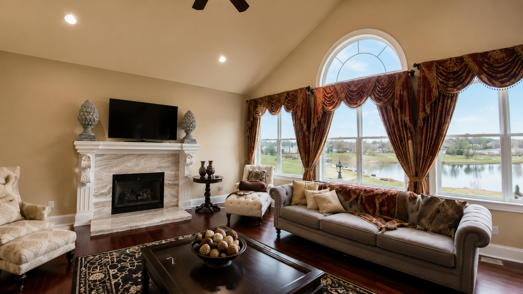 Elegant living room with fireplace, large window, and patterned curtains overlooking a waterfront view