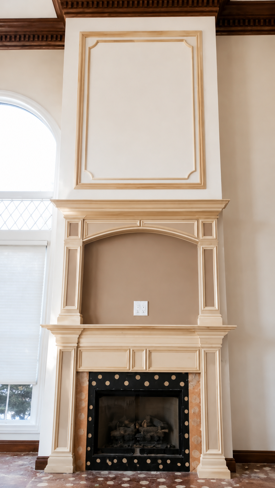 Elegant cream fireplace with black firebox and arched mantel in a bright room