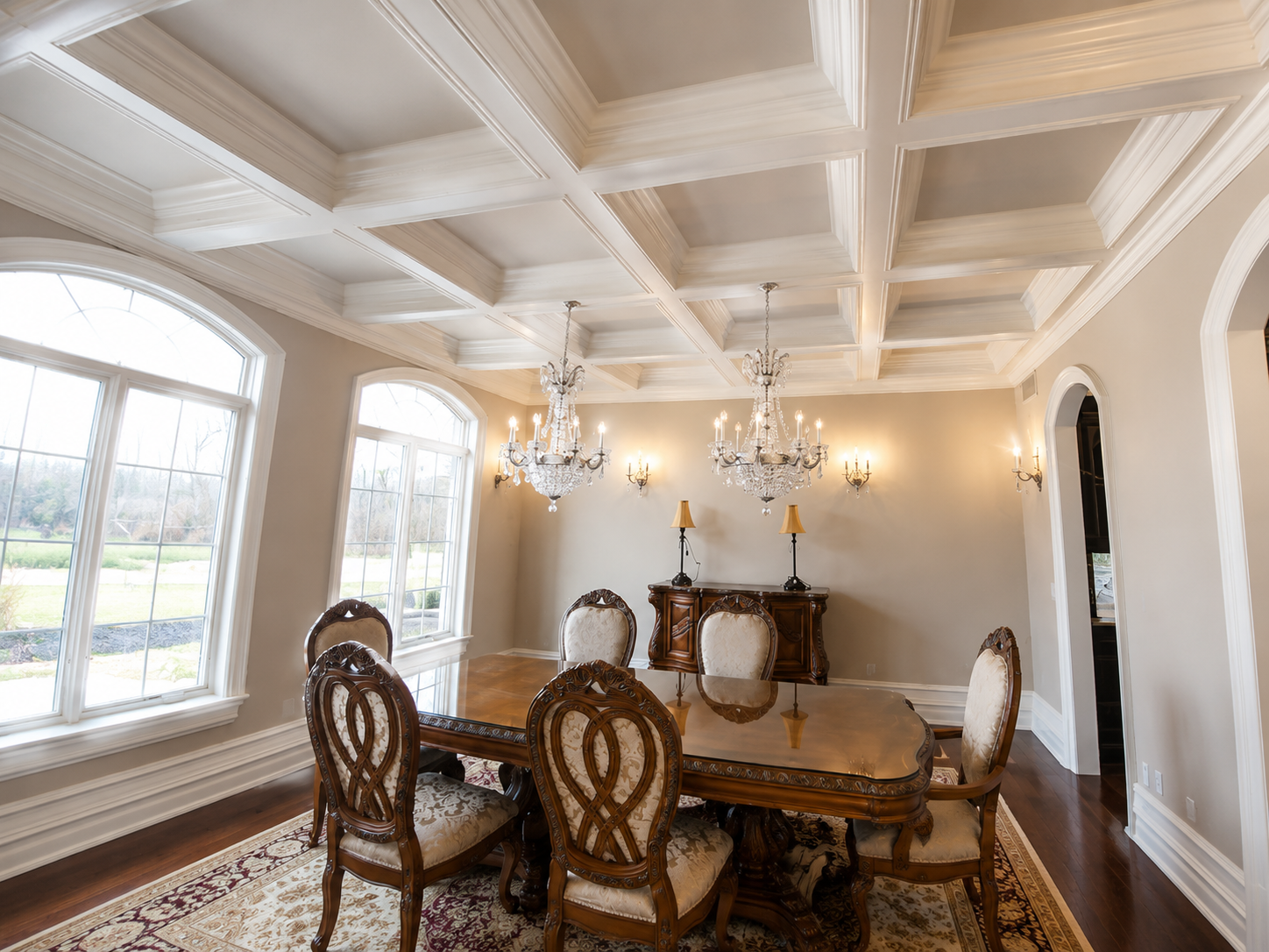Elegant dining room with ornate chairs, chandelier, and large arched windows in soft light