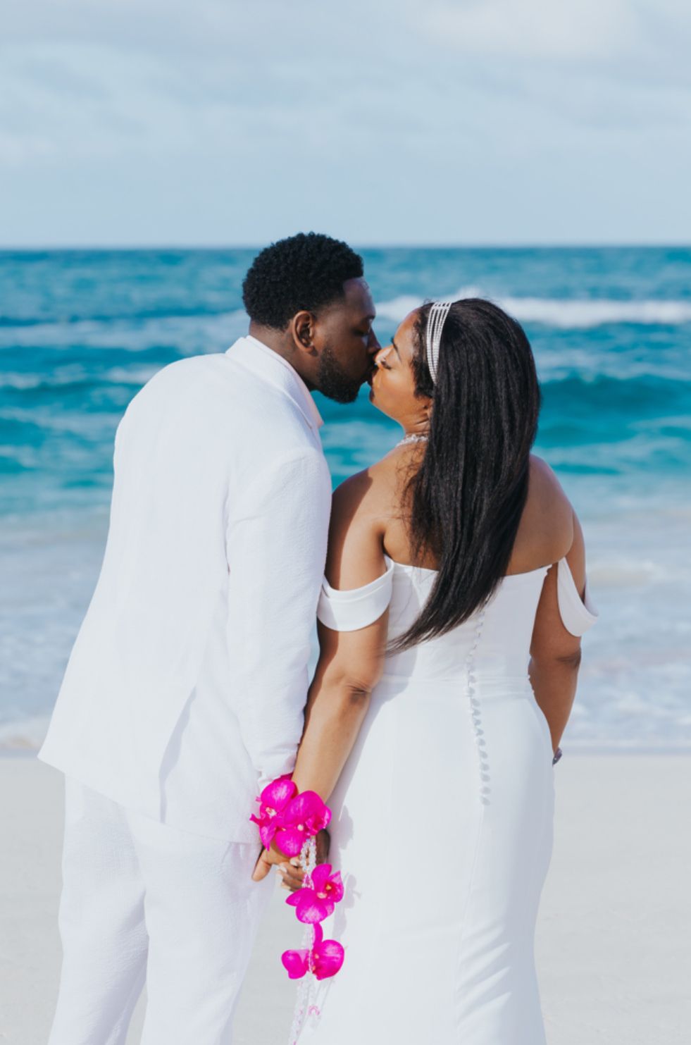 bride and groom kissing in front of the ocean