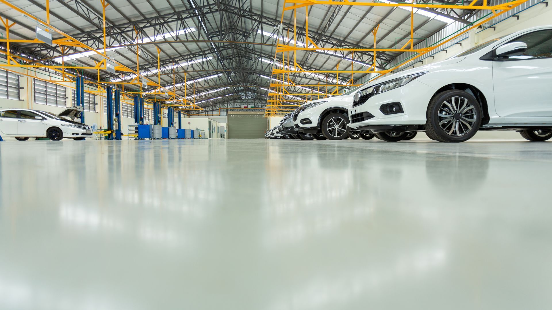 Cars in a dealership showroom, with a yellow car in the front.
