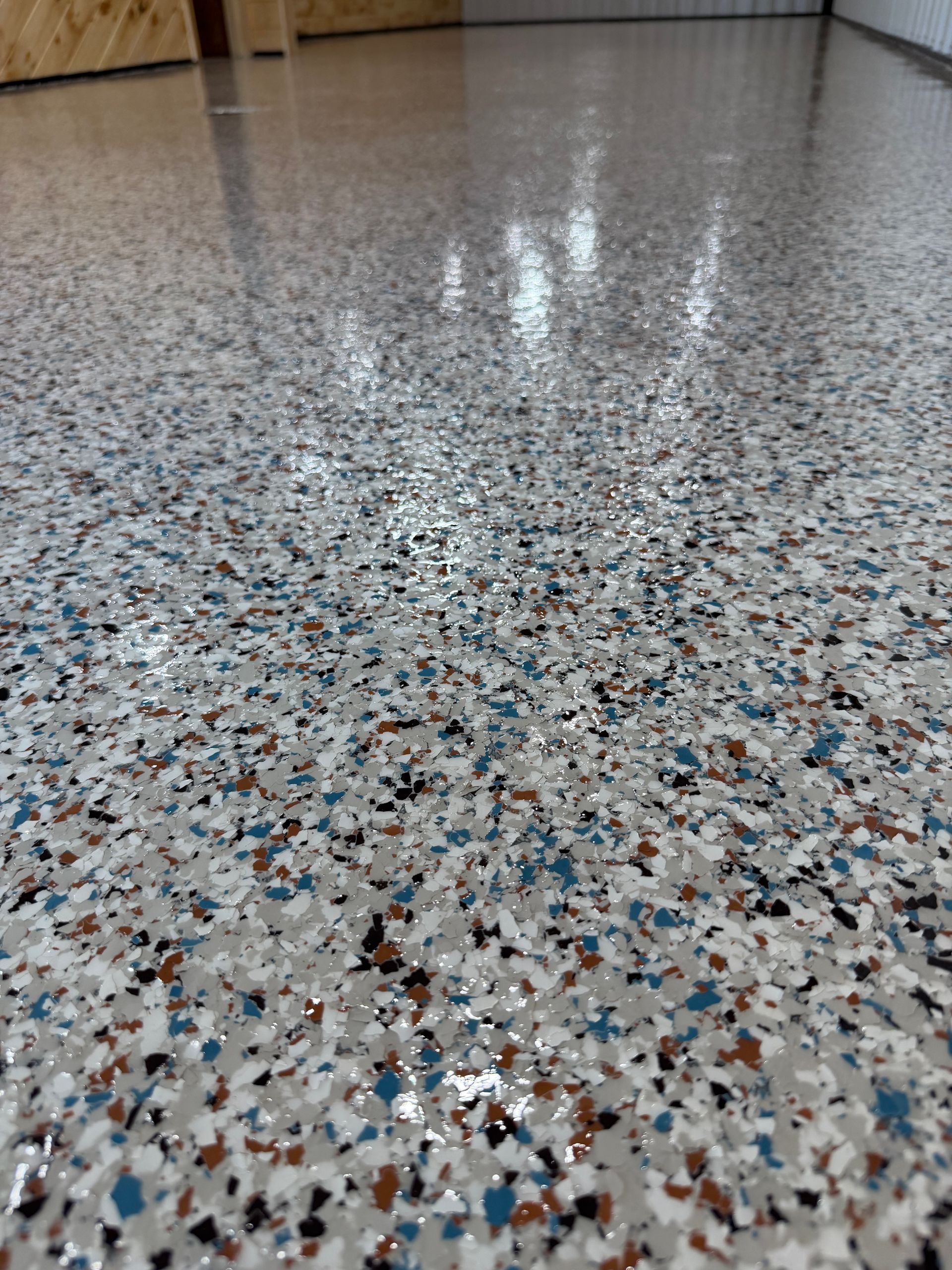 Mall hallway with a colorful, abstract floor design, light fixtures, and storefronts.