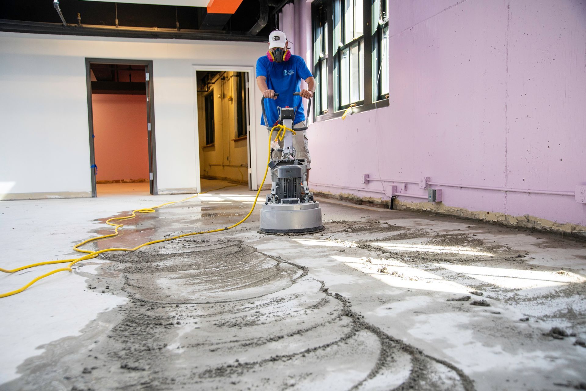 Interior view of a modern office space with tall windows, tables, and chairs. Black hanging lights.