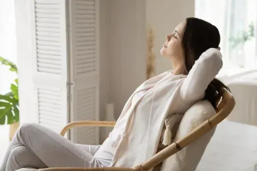 A woman is sitting in a chair with her eyes closed.