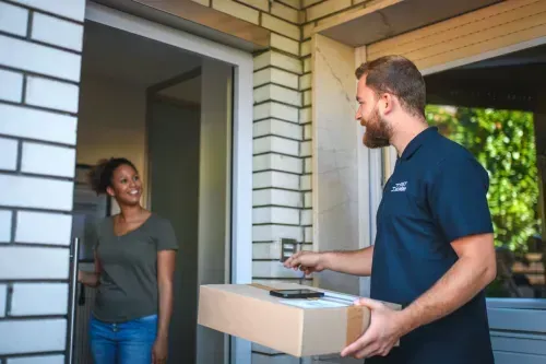 A man is delivering a package to a woman in a doorway.