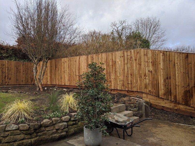 Pressure-treated timber fencing along sloping land
