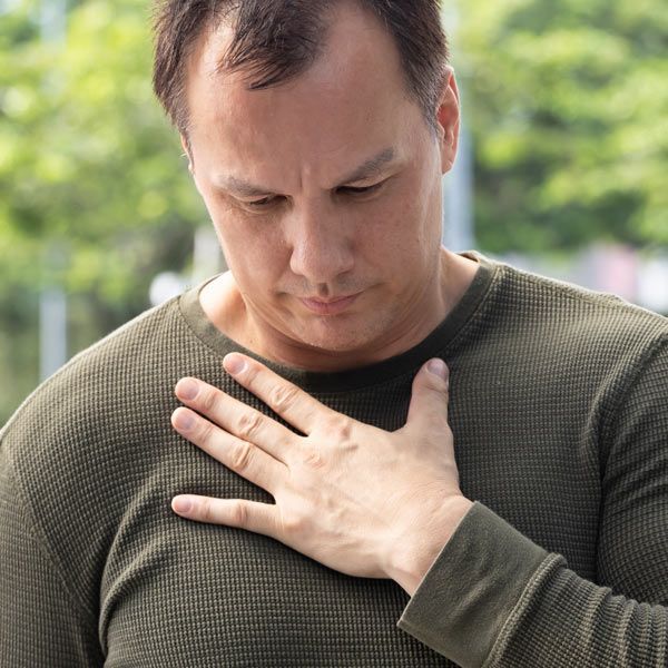 Man with GERD is holding his chest from discomfort