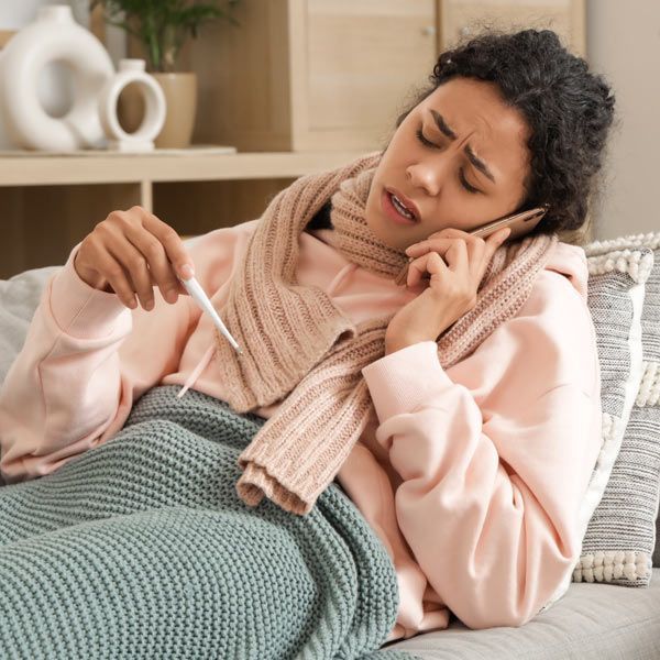 Woman with immune deficiency is sick in bed taking her temperature