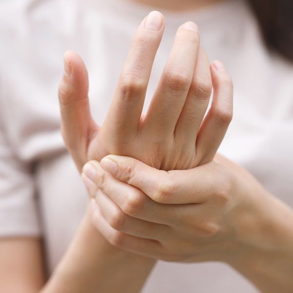 A person holding their own wrist with the opposite hand, suggesting arthritis pain or discomfort.