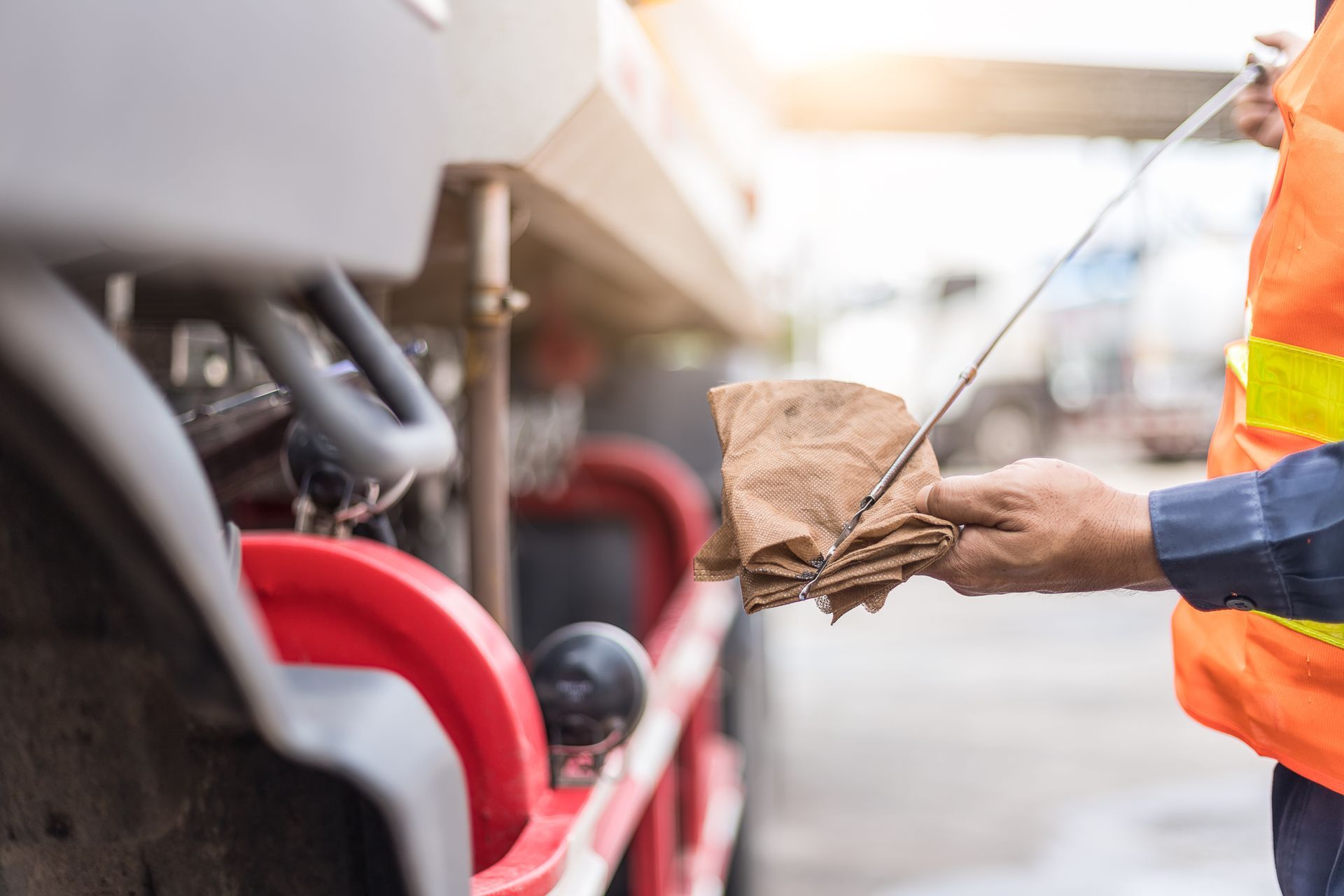 A man is checking the oil of a truck with a dipstick towel.