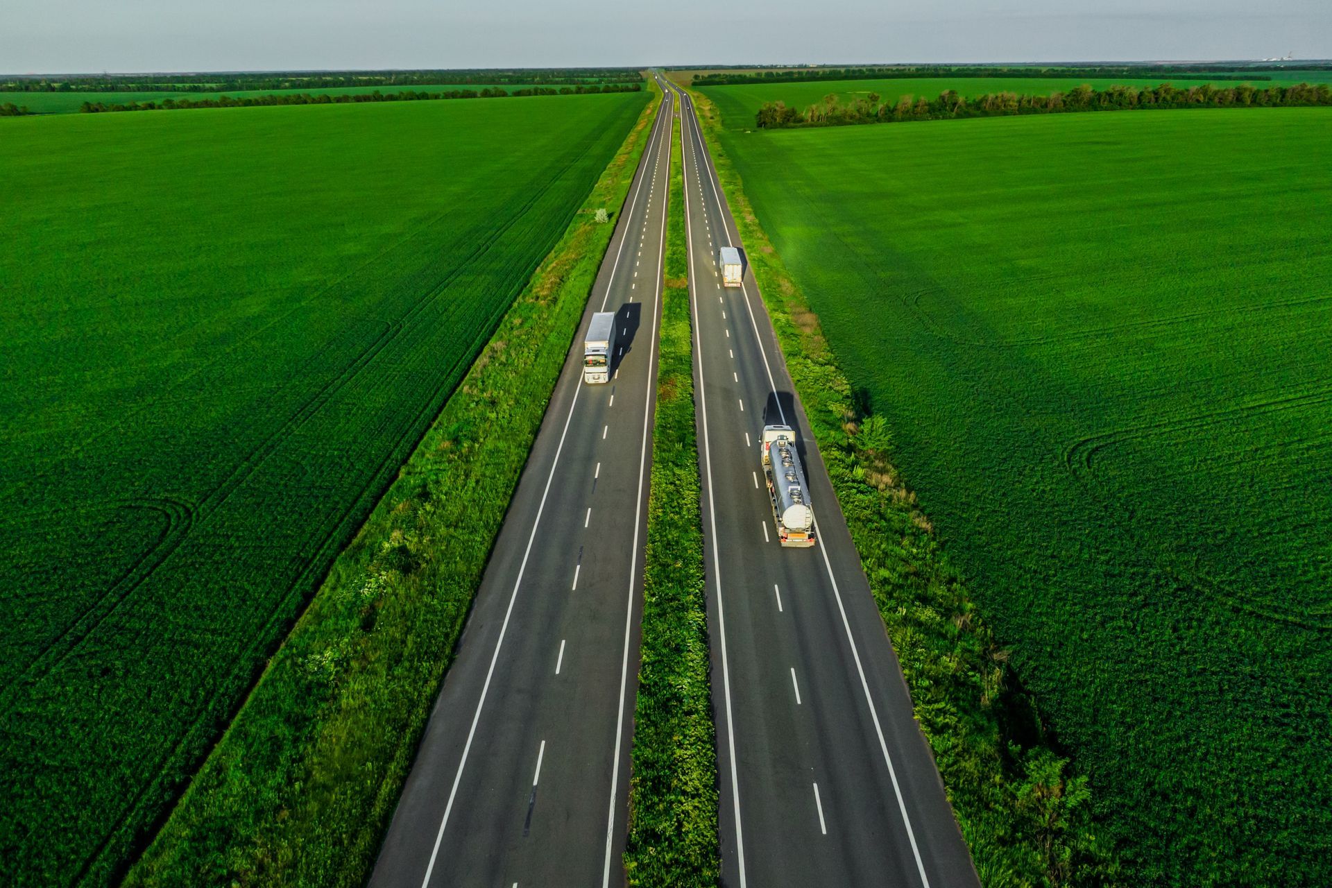 An aerial view of a highway surrounded by green fields.