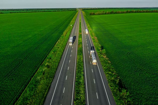 An aerial view of a highway surrounded by green fields.