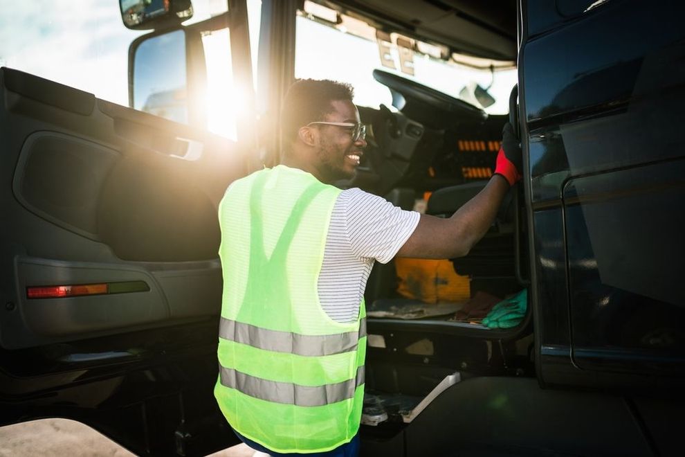 A man in a yellow vest is working on a truck.