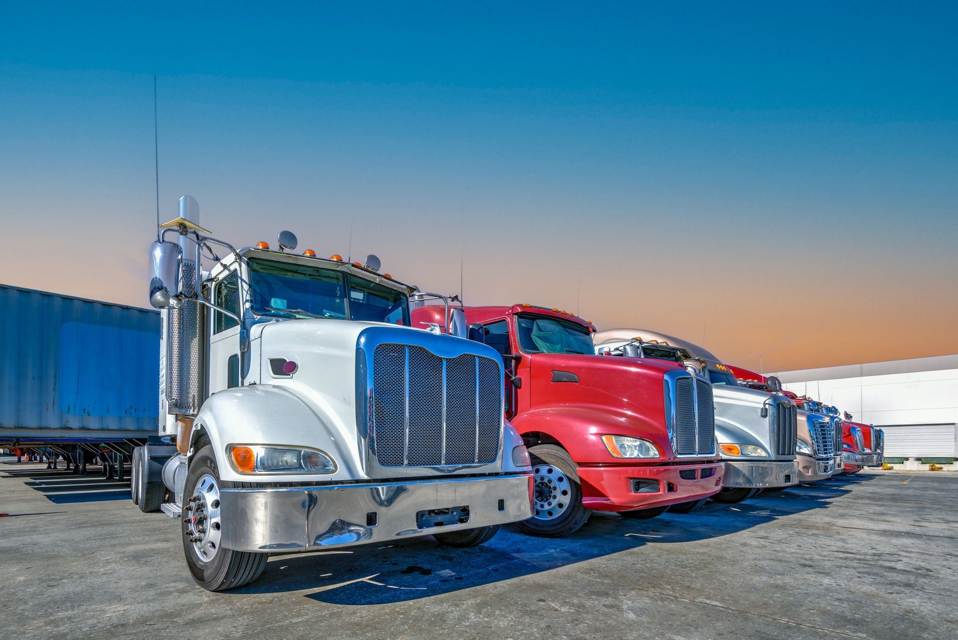 A row of semi trucks parked next to each other in a parking lot.